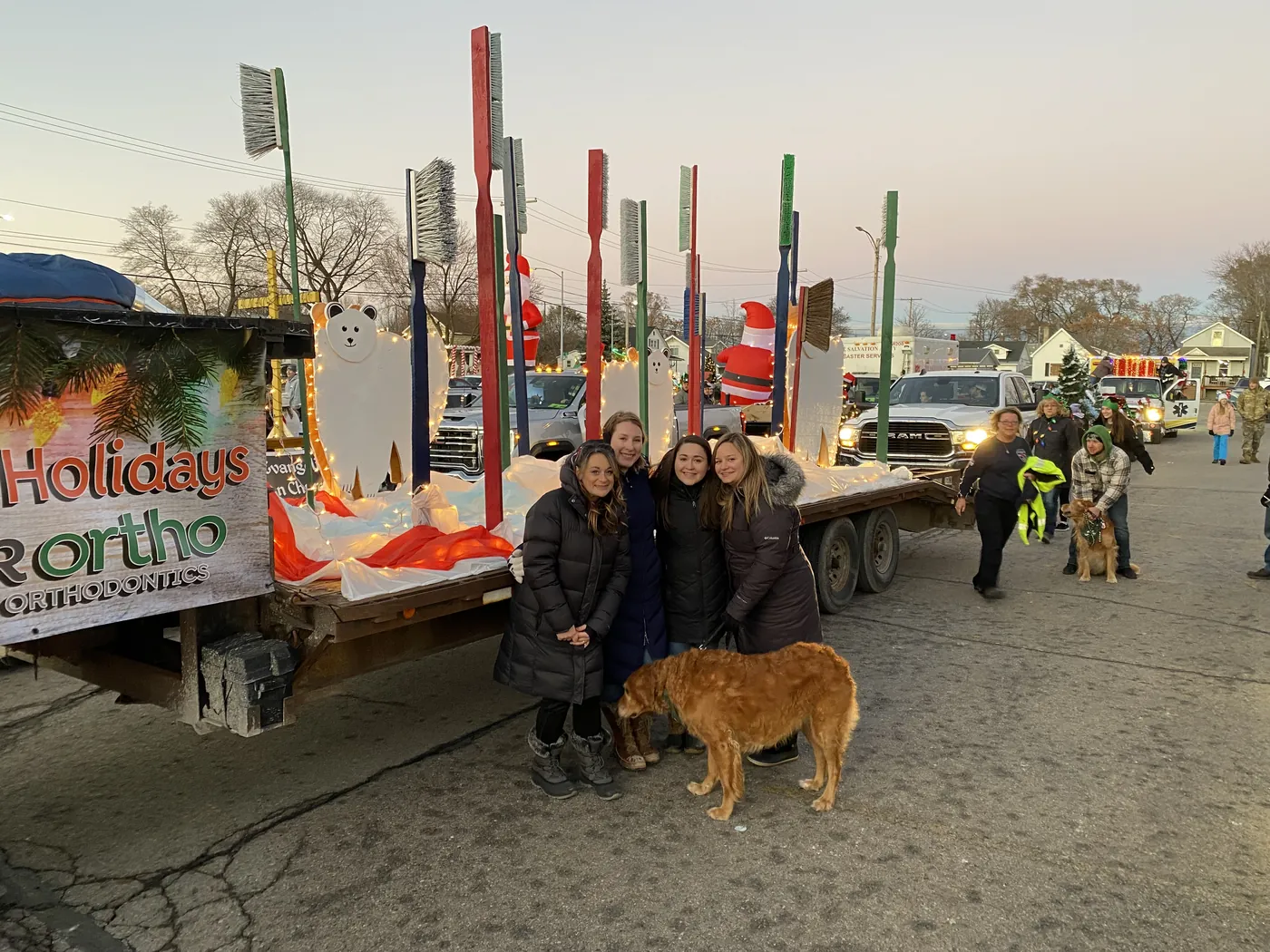 Sytek Ortho team members and a golden retriever beside the parade float