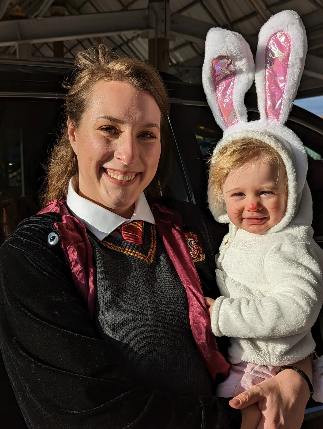 A Sytek Ortho team member in costume holding a toddler at the Trunk or Treat event